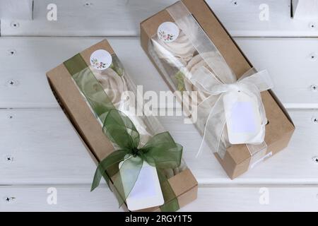 Homemade marshmallows in paper gift boxes. Zephyr flowers. The boxes are tied with a ribbon tied into a bow. Tag for text. Stock Photo