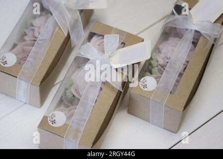 Homemade marshmallows in paper gift boxes. Zephyr flowers. The boxes are tied with a ribbon tied into a bow. Three boxes. Stock Photo