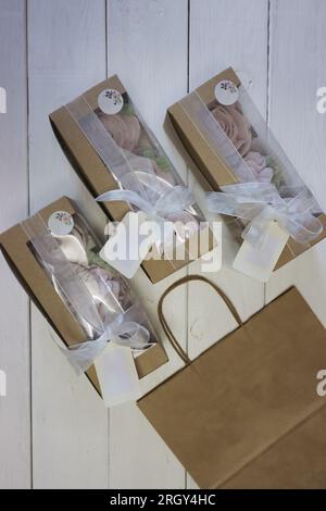 Homemade marshmallows in paper gift boxes. Zephyr flowers. The boxes are tied with a ribbon tied into a bow. Three boxes. Stock Photo