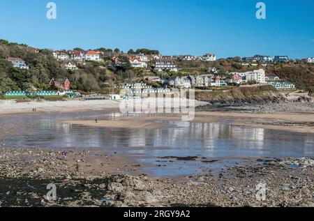 Langland Bay on the AONB Gower peninsula, south Wales in February with sunshine, a clear blue sky and reflections in the wet beach sand near Swansea Stock Photo