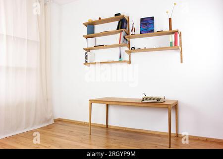 A used midcentury bookshelf original from the 60s mounted on a white wall. Filled with books and other rare accessories in scandinavian design second Stock Photo