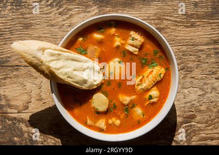 A bowl of fish stew or bouillabaisse, that has been made with king scallops, smooth hound, anglerfish also known as monkfish and gurnard fillets. Serv Stock Photo