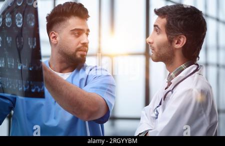 Doctors and an intern examine an X-ray of a patient. MRI scans of brain activity and scientists. Stock Photo