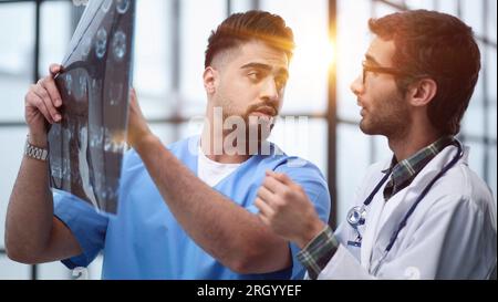 Doctors and an intern examine an X-ray of a patient. MRI scans of brain activity and scientists. Stock Photo