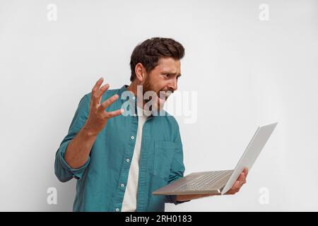 Stressful man looking on laptop during work and screaming gesturing with his hand Stock Photo