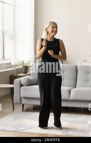 Happy attractive blonde mature woman dancing at home Stock Photo