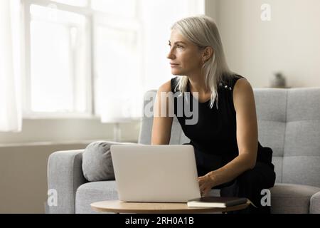 Serious thoughtful mature business woman working at laptop Stock Photo