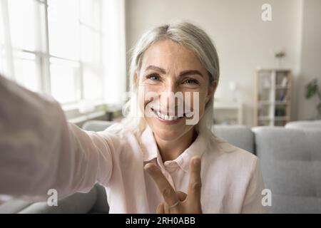 Happy positive blonde senior woman taking selfie picture Stock Photo