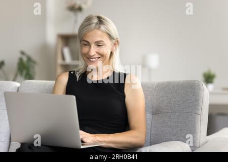 Cheerful senior business woman working from home, using application Stock Photo