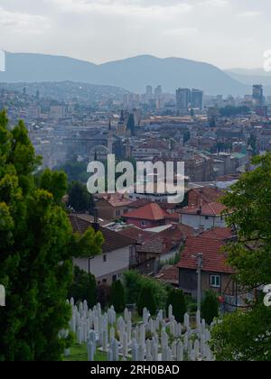 Elevated view over a cemetery and the city of Sarajevo with modern high rises and mountains in background, Bosnia and Herzegovina, August 12,2023. Stock Photo