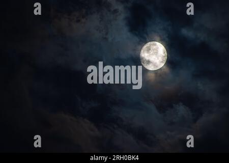 Full moon in the clouds against a black sky Stock Photo