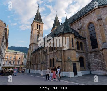 People walk past the Sacred Heart Cathedral, a Catholic Church in the city of Sarajevo, August 12, 2023. Stock Photo