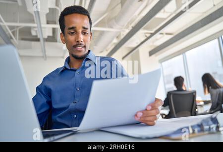 Busy young African American business man working in office checking papers. Stock Photo