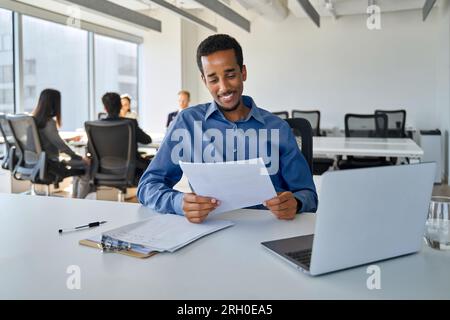 Happy young African American business man working in office checking documents. Stock Photo