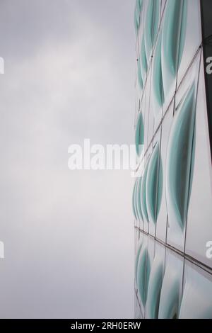 Architectural image of a glass facade with a reflective curved shape on a cloudy day. Abstract image ideal to represent new architectural ideas, moder Stock Photo