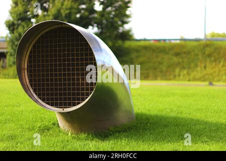 Curved circular piece emerging from a plane of full green grass. Ventilation. Ideal if you work in air conditioners or something related to ventilatio Stock Photo