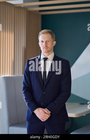 Confident young professional business man standing in office. Vertical portrait. Stock Photo