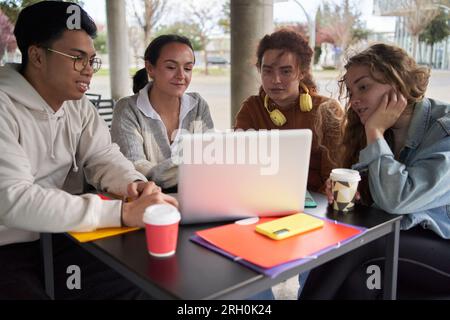 Group of students sharing a laptop to do homework Stock Photo