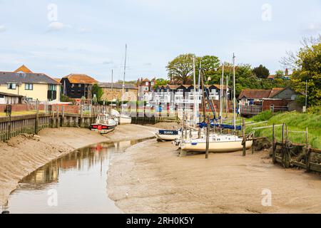 Boats moored resting on the muddy banks at low tide on the River Rother at Rye Harbour, a small coastal village near Rye town in East Sussex Stock Photo