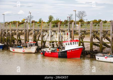 A red fishing boat moored at low tide on the River Rother at Rye Harbour, a small village near Rye town near the coast in East Sussex Stock Photo