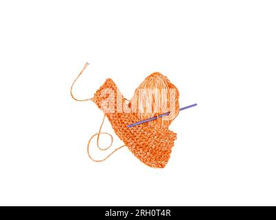 On a white backdrop, an isolated purple crochet hook accompanies pumpkin colored yarn. Stock Photo