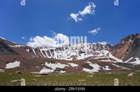 Rock mountains are covered with melting snow. Summertime Stock Photo