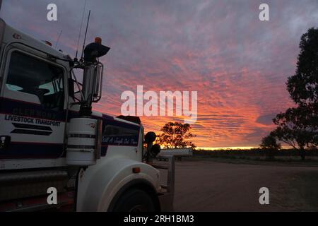 vivid red sunset sky seen behind a truck (lorry) cab in the outback of queensland, australia Stock Photo