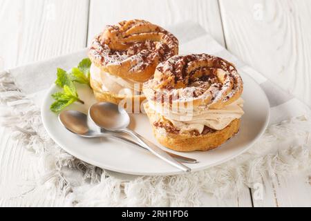 Paris-Brest is an indulgent iconic French dessert made of choux pastry and hazelnut praline closeup on a plate on the wooden table. Horizontal Stock Photo