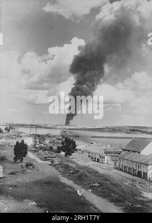 Malaya Campaign, December 1941 – February 1942. A photo taken by the invading Imperial Japanese Army shows a large hole blown in the causeway that once connected Singapore with Johor as smoke from a Japanese bombardment near Seletar billows in the distance, circa February 1942. On January 31 as the Japanese drew nearer, British troops in Johor had withdrawn from their positions into Singapore and detonated the causeway behind them in an attempt to cut off the Japanese advance into Singapore. Stock Photo