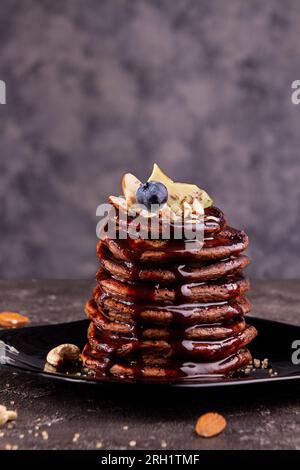 Vegan pancakes based avocado with cocoa and date syrup. Vegan healthy sweet food. Dark background Stock Photo