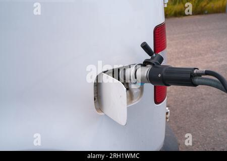 White vehicle being refilled with natural gas in CNG filling station. Finland. Stock Photo