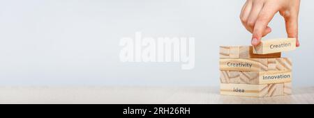 Creativity concept. Hand places the wooden rectangles next to the others, creating a tower of wooden cubes with the words Creativity, Innovation and Stock Photo
