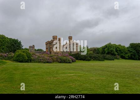 Lews castle set above the Town of Stornoway in the Outer Hebrides sitting on a grassy inline under flowering Azaleas on an overcast day in June. Stock Photo