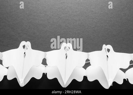 Trick or Treat concept. Holiday composition with halloween garland decorations ghosts isolated on black background. Preparation for Halloween party. Stock Photo