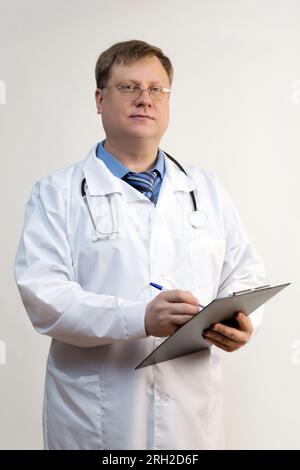 Smart doctor in a white coat standing writes on paper. Stock Photo