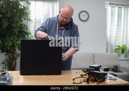 IT specialist repairs desktop computer that stands on desk Stock Photo