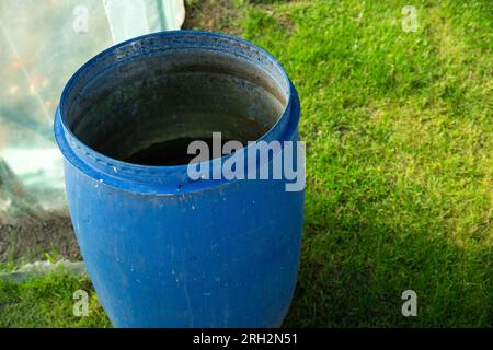 A large blue plastic barrel standing on the green grass Stock Photo