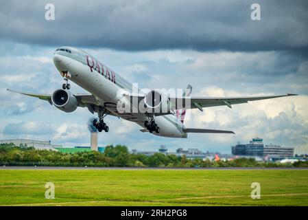 Qatar airways Boeing 777-3DZ/ER.with Manchester airport terminbal in the background. Stock Photo