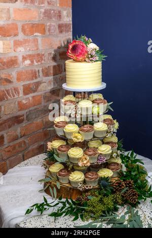 Wedding cake with cupcakes and fresh flowers Stock Photo