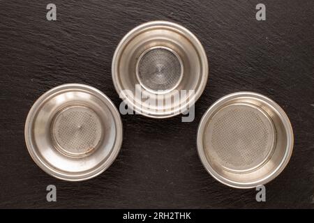 Three metal sieves for a coffee maker on a slate stone, macro, top view. Stock Photo
