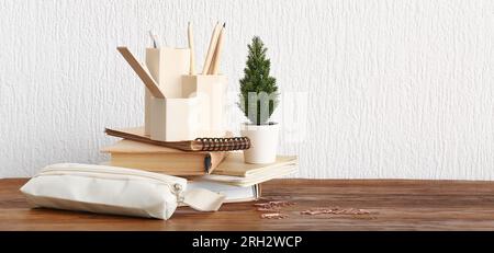Stylish cup with stationery, books and houseplant on table against white background. Banner for design Stock Photo