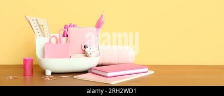 Stylish cup with stationery on table against yellow background. Banner for design Stock Photo