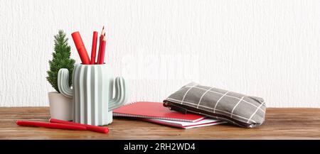 Stylish cup with stationery and houseplant on table against light background Stock Photo