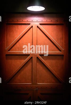 Red robust door with light from above. Brown dark Door as a background Stock Photo