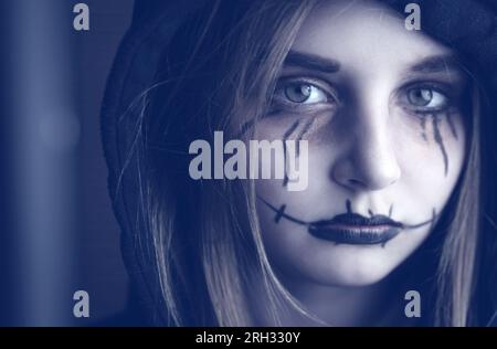 Little girl with spooky Halloween makeup looking at camera. Creepy kid's portrait. Stock Photo