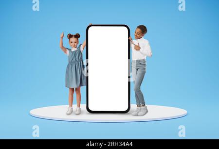 Two Little Girls Standing Near Huge Blank Smartphone With White Screen Stock Photo