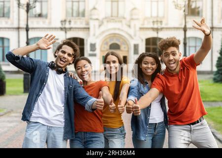 We Recommend. Group Of Cheerful Multiethnic Students Gesturing Thumbs Up At Camera Stock Photo