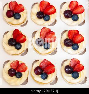 Close up on a set of cupcakes decorated with strawberry slices, fresh raspberry and blueberry on gift box Stock Photo