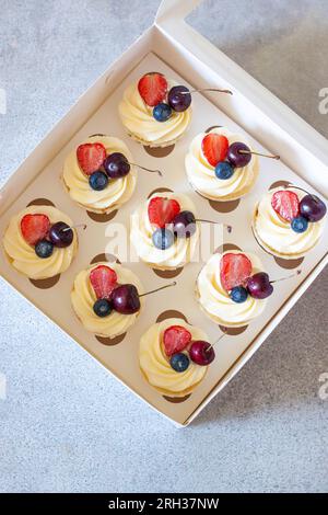 Close up on a set of cupcakes decorated with strawberry slices, fresh raspberry and blueberry on gift box Stock Photo