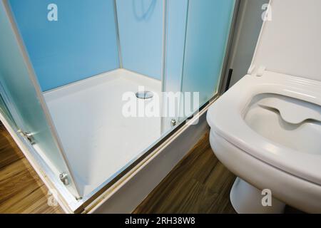 The shower cabin is located next to the toilet bowl in the bathroom interior. Stock Photo